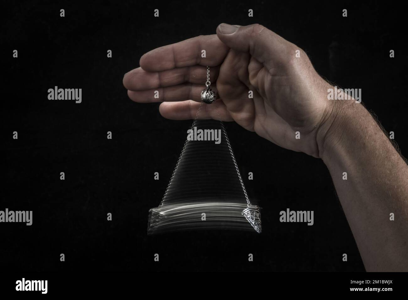 Hand holding a swinging pendulum Stock Photo Alamy