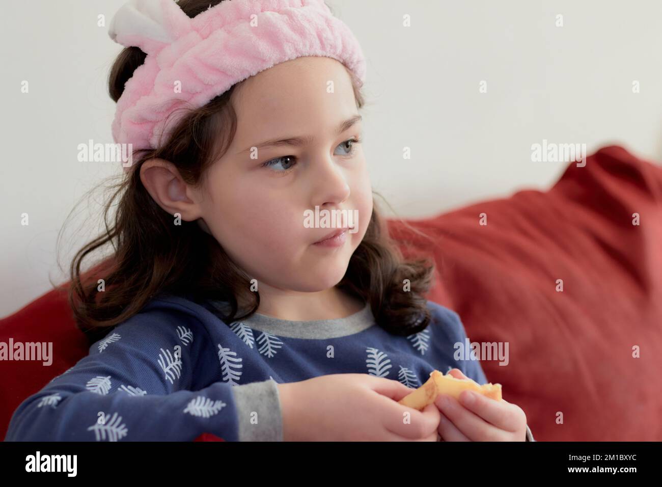cute little girl in a pink head dress is eating crepes on the couch ...