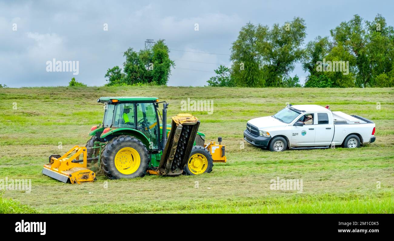 NEW ORLEANS, LA, USA - SEPTEMBER 6, 2022: Tractor cutting grass on the Mississippi River Levee and truck belonging to the Flood Protection Authority Stock Photo