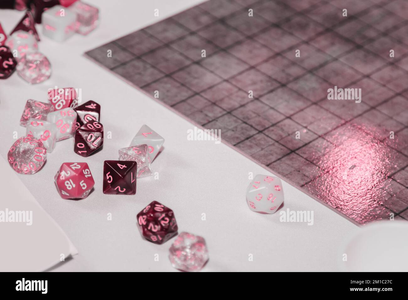A set of polyhedral dice used for role playing games such as Dungeons Dragons. A fresh classic for 2023 in Viva Magenta. Color concept of the year. Stock Photo
