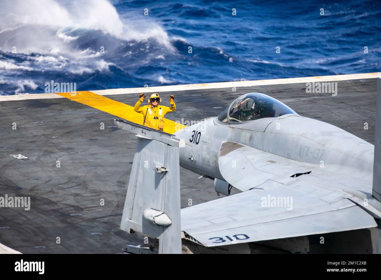 221210-N-AT895-1027 PACIFIC OCEAN (Dec. 10, 2022) A U.S. Navy Aviation Boatswain's Mate (Handling) directs an F/A-18E Super Hornet from the “Kestrels” of Strike Fighter Squadron (VFA) 137 on the flight deck of the aircraft carrier USS Nimitz (CVN 68). Nimitz is underway conducting routine operations. (U.S. Navy photo by Mass Communication Specialist 1st Class Nathan Laird) Stock Photo