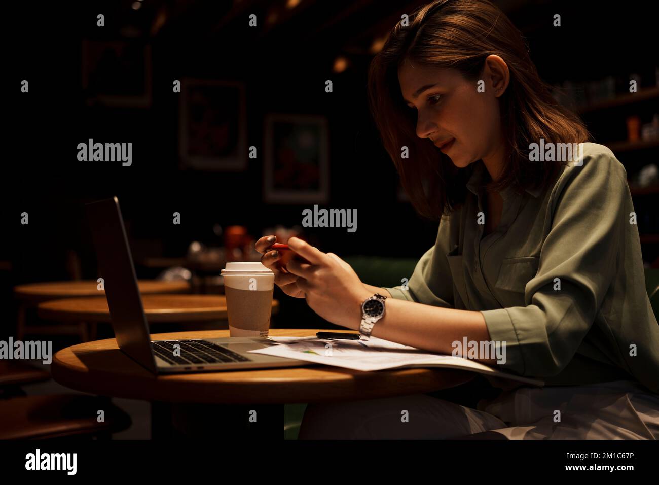 Young woman using smart phone and laptop at cafe. Stock Photo