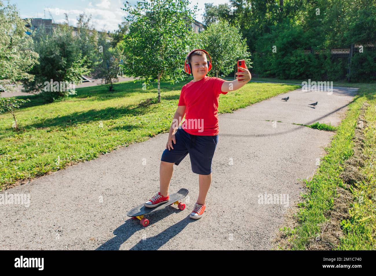 Chubby ten years old boy spends free time training skating in the city park. Boy looking on