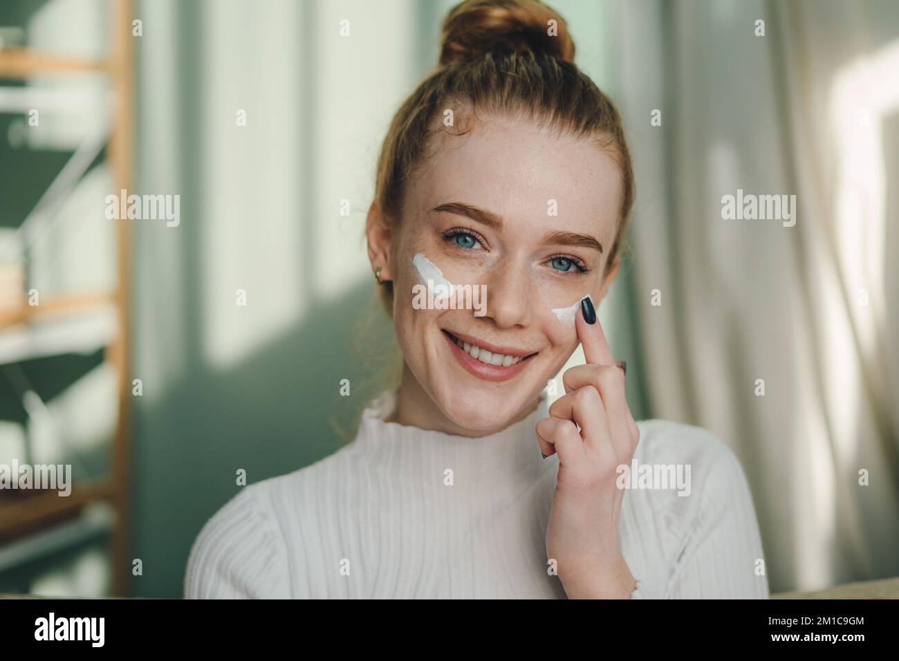 Close up portrait of a ginger girl with freckles applying moisturizing