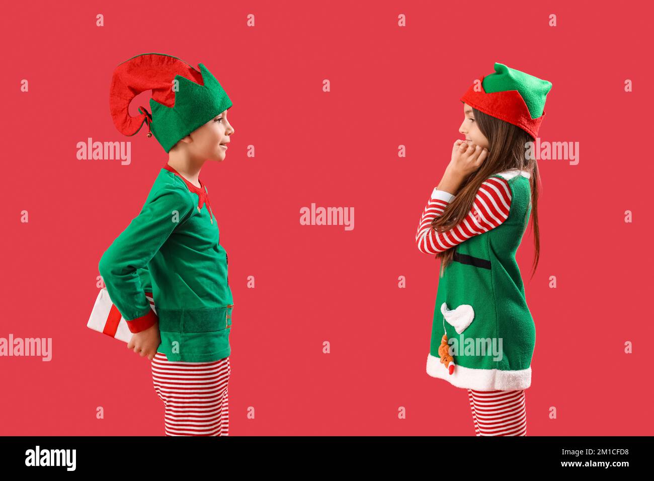 Little boy in elf pajamas surprising his sister with Christmas gift on