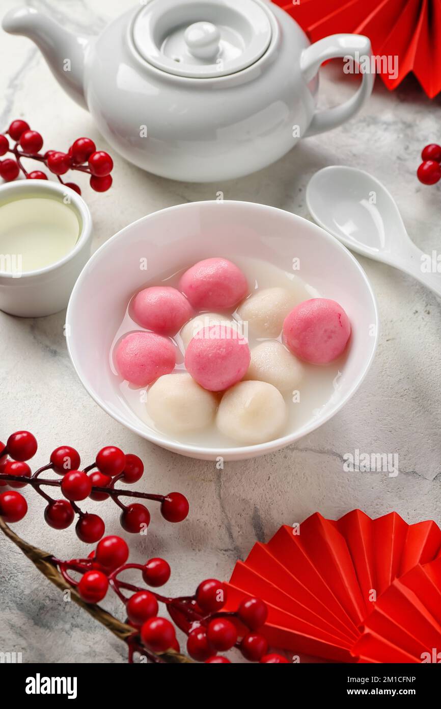 Bowl of tangyuan, cup, teapot and Chinese decor on light background ...