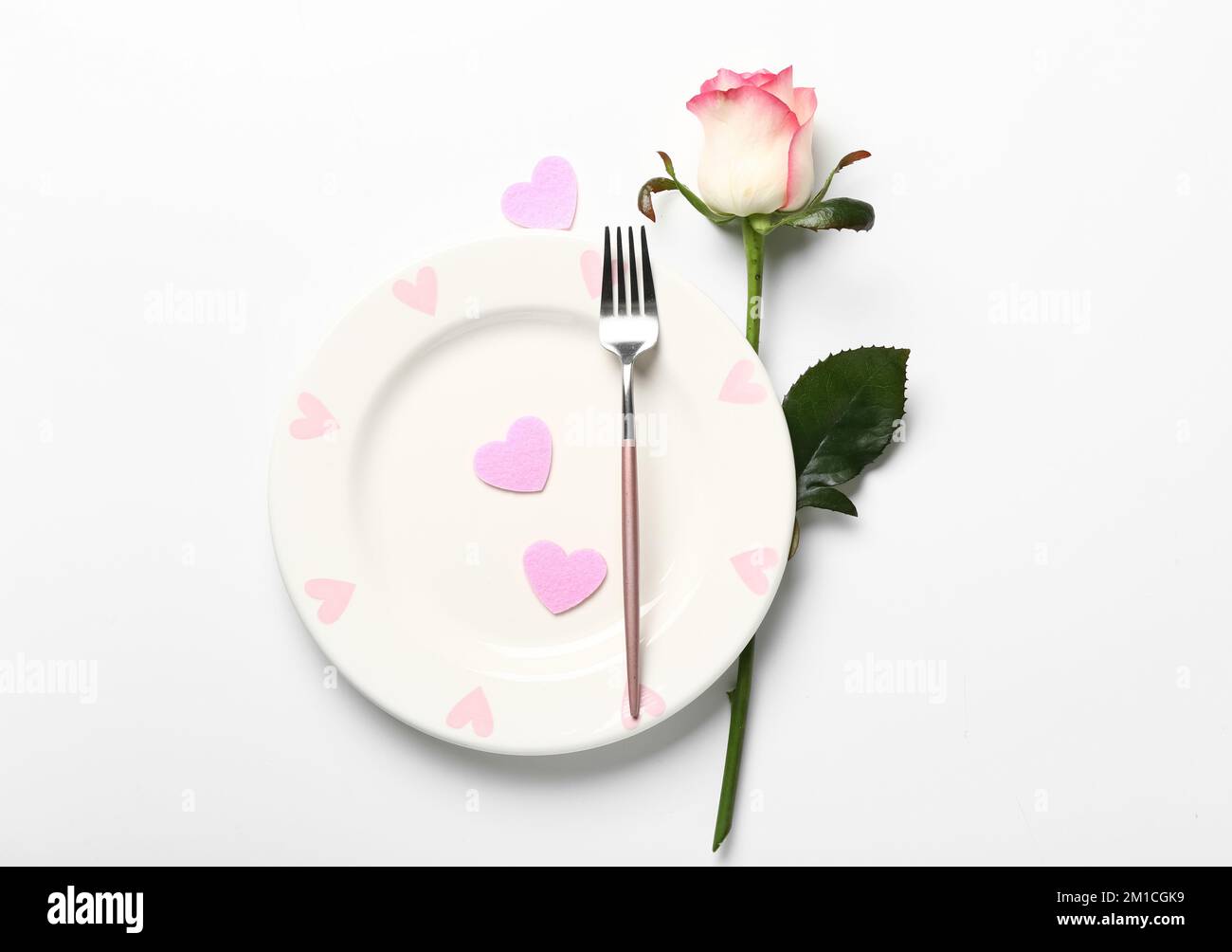 Table setting for Valentine's Day with pink hearts and rose on white ...