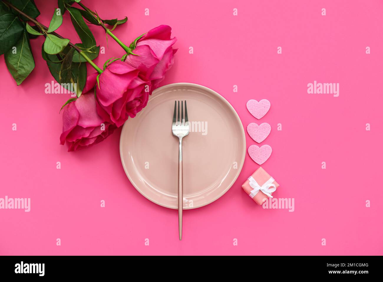 Table setting for Valentine's Day with roses and gift on pink ...