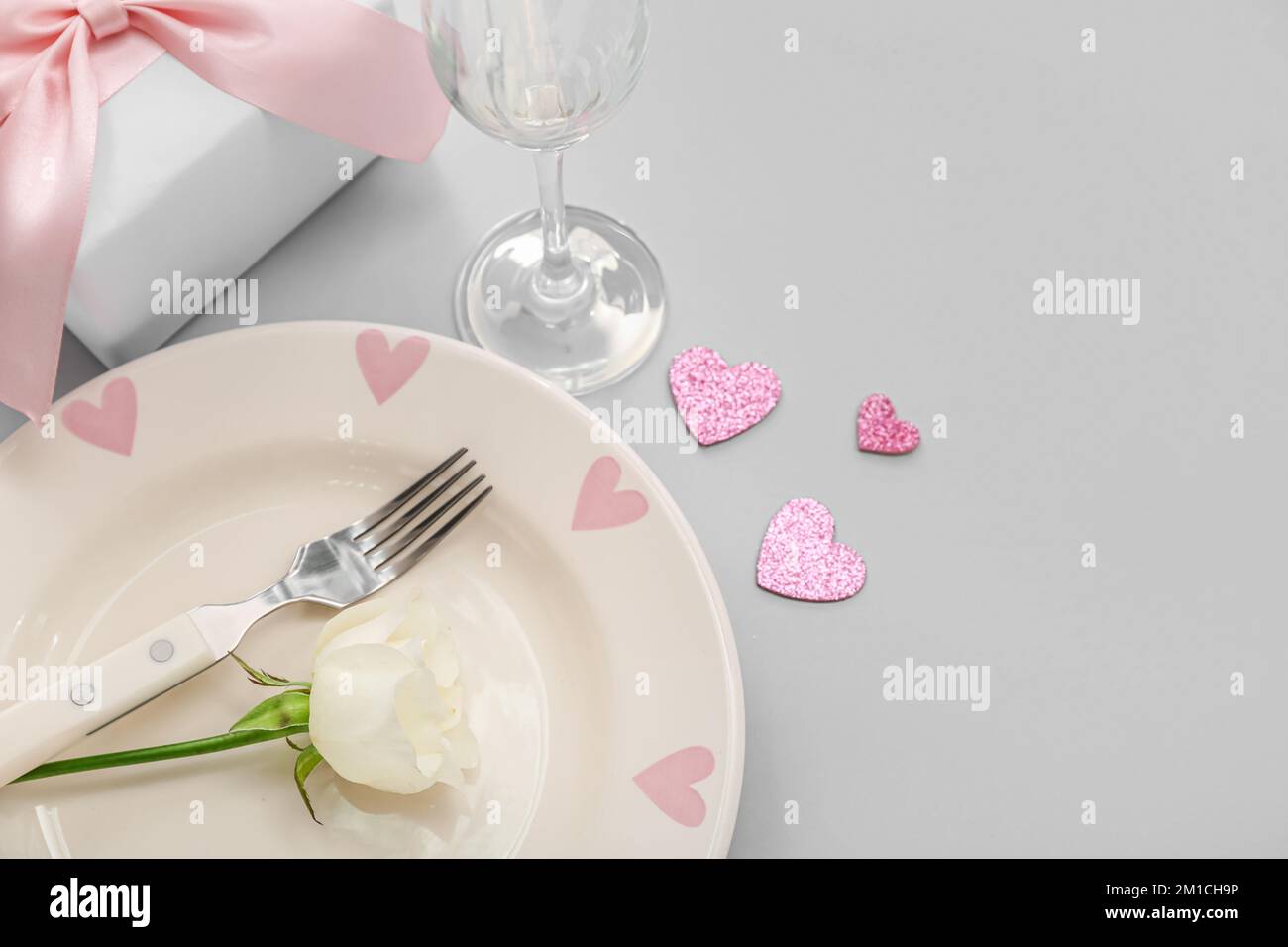 Table setting for Valentine's Day with hearts, rose and gift on grey ...
