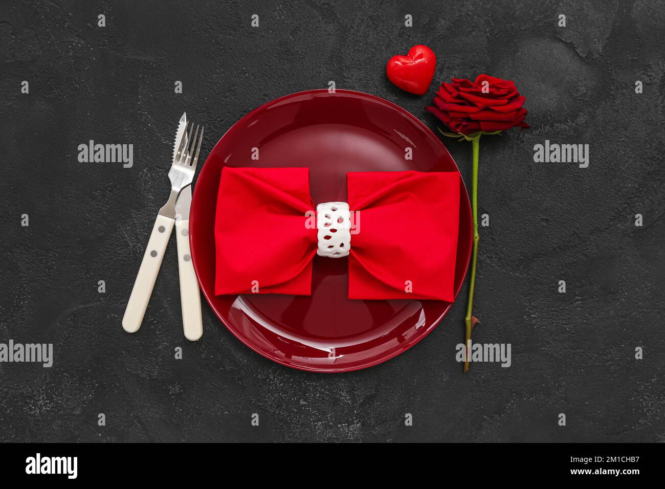 Table setting for Valentine's Day with heart and rose on dark ...