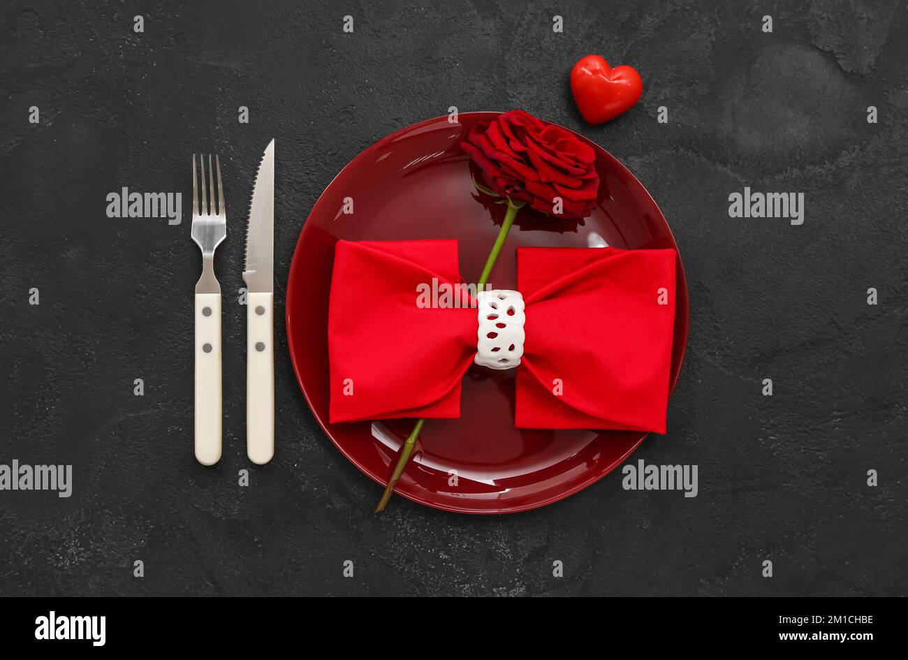 Table setting for Valentine's Day with heart and rose on dark ...