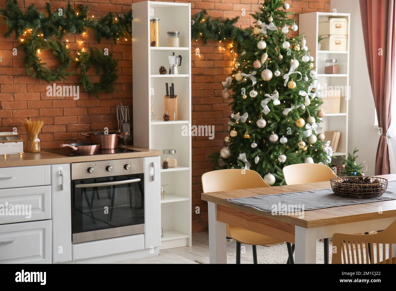 Interior of kitchen with glowing Christmas tree, dining table and