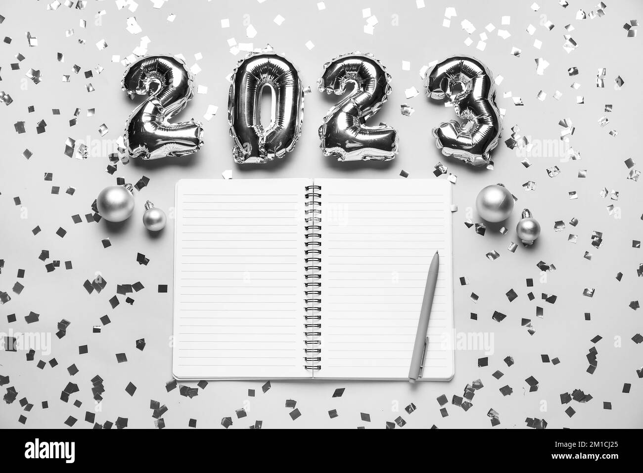 Composition with blank open notebook, pen, confetti and figure 2023 made of balloons on light background Stock Photo
