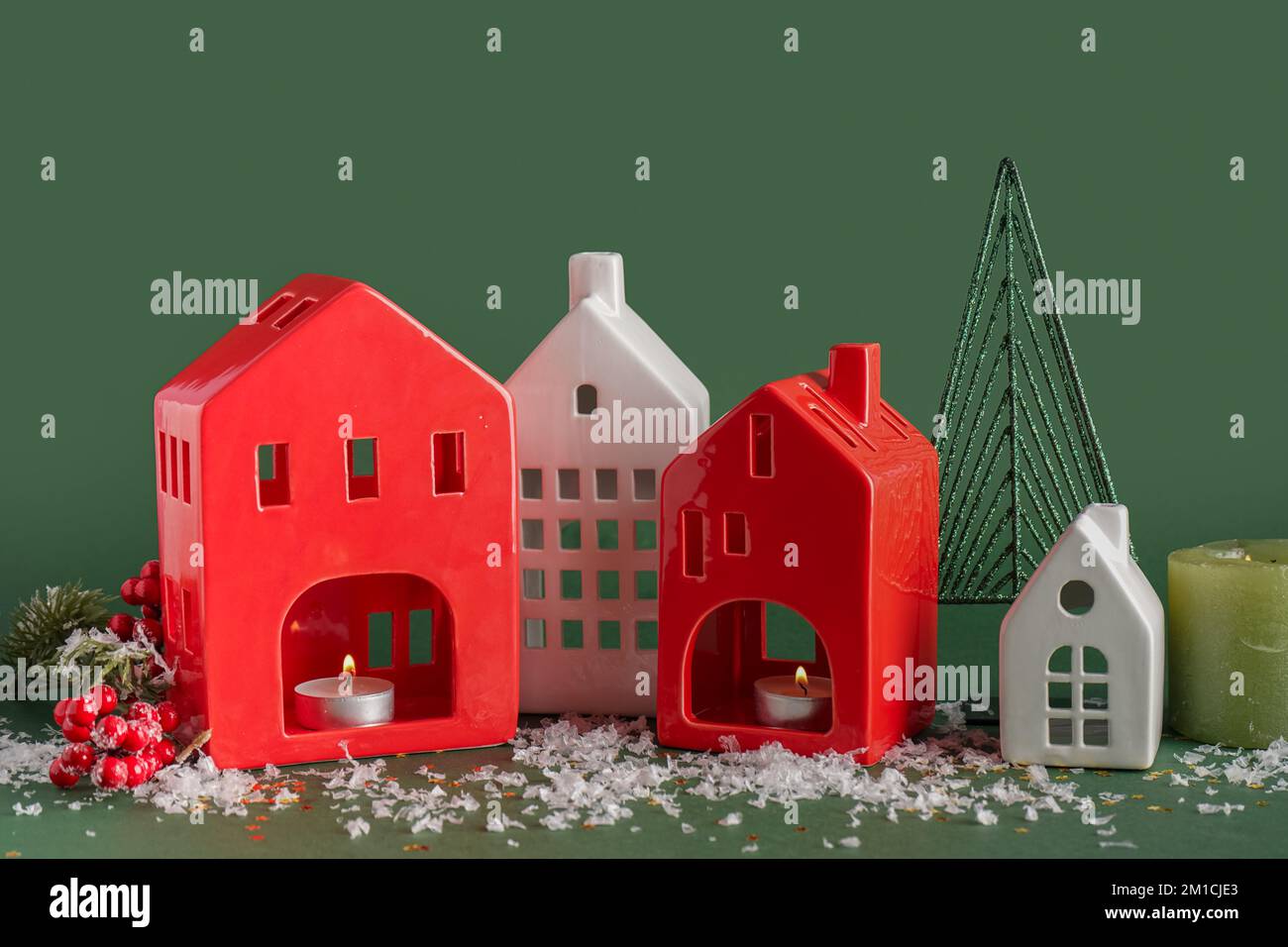 House shaped candle holders with snow on green background Stock Photo