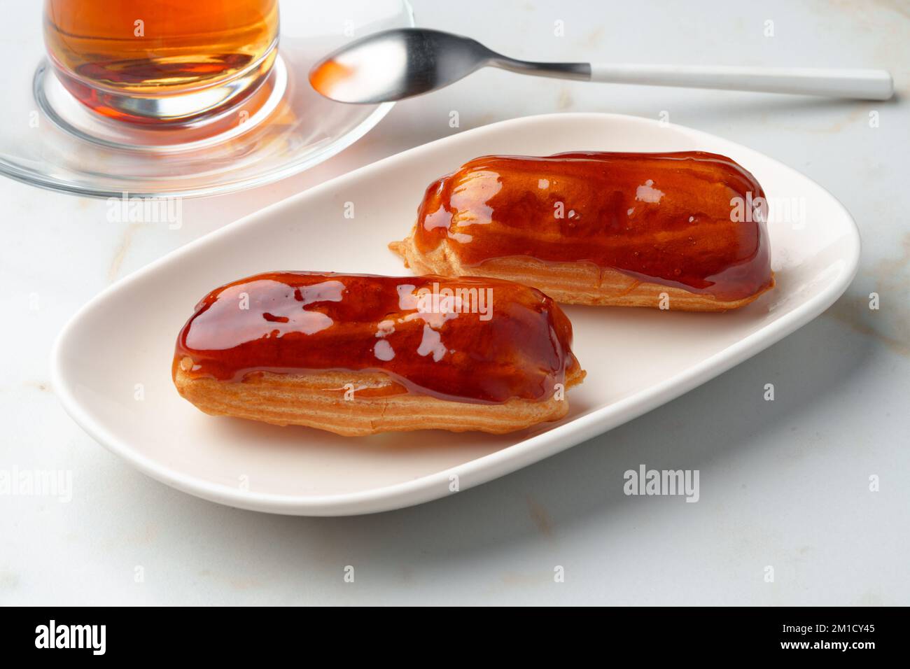 Two caramel eclairs on a white plate Stock Photo