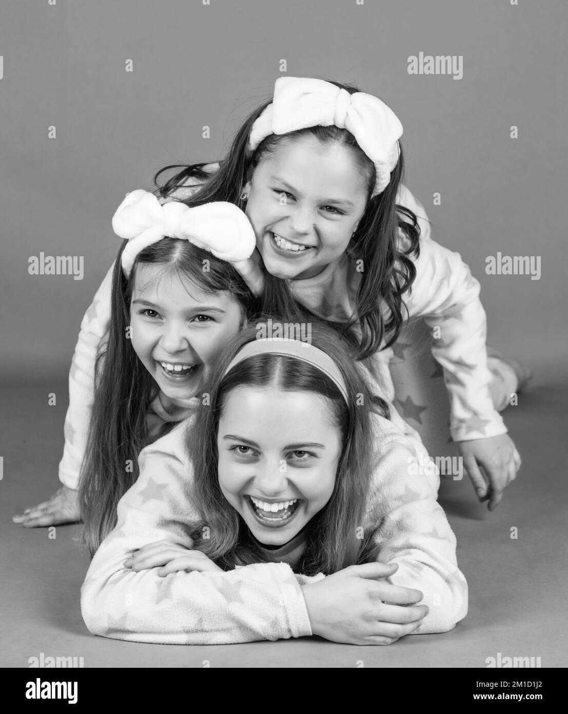 Happy childrens laughter. Happy girls laughing lying close on each other. Pajama party. Stock Photo