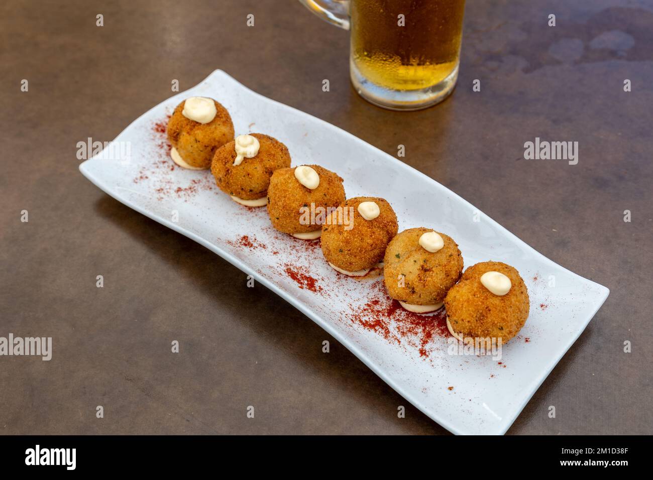 A closeup of fried mozzarella balls served with a glass of beer in a