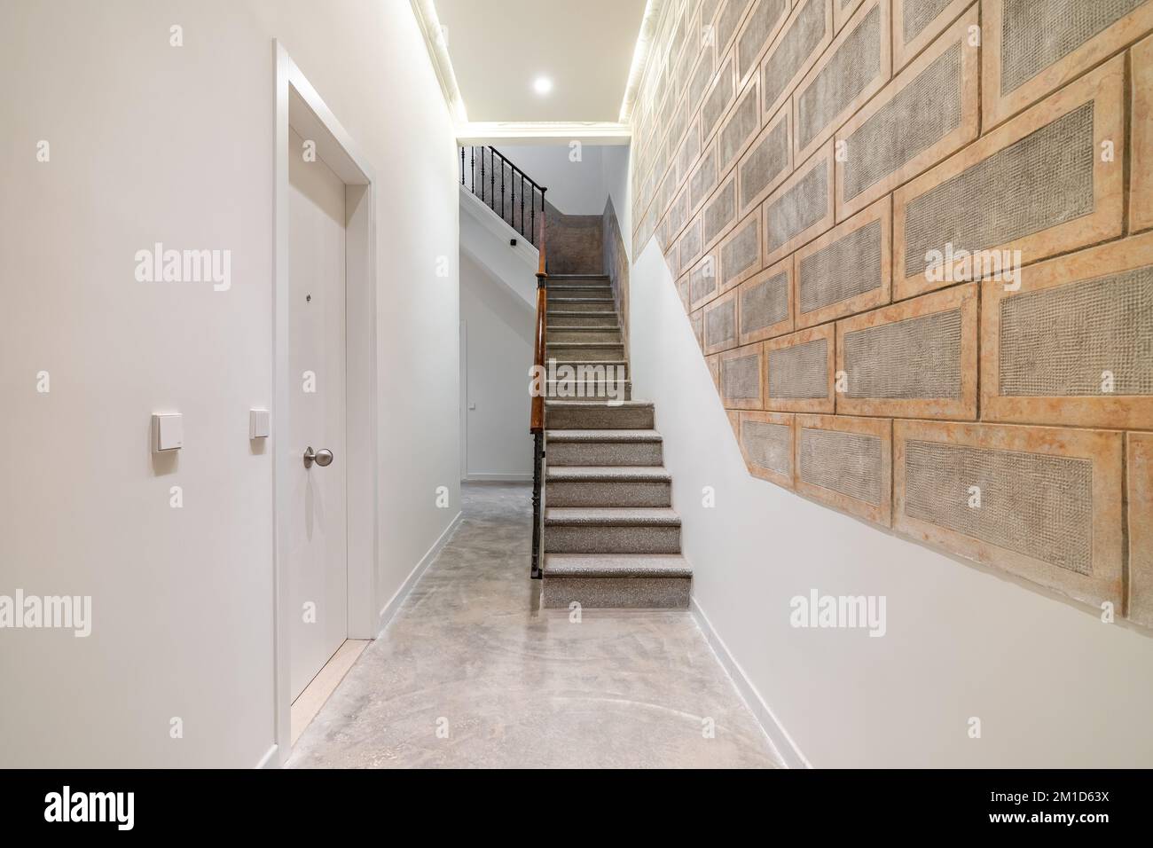 Stone staircase with wooden railing leading to second floor in bright ...