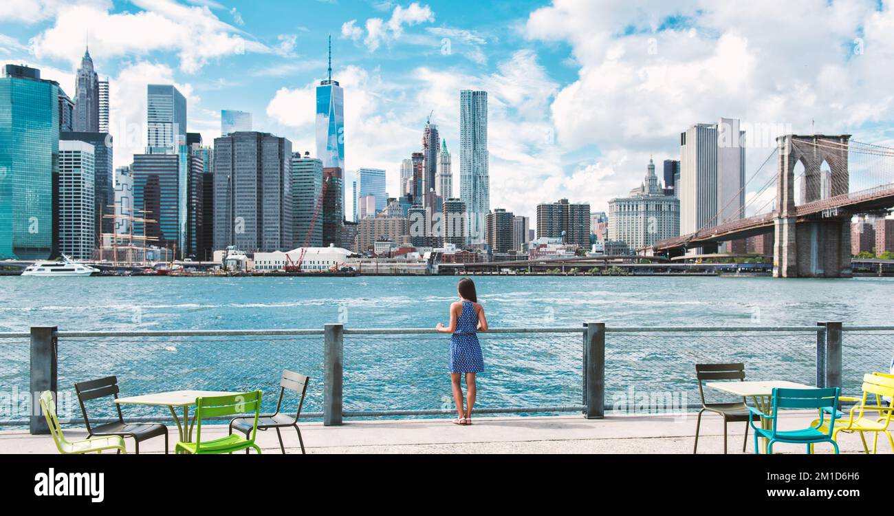 New York city Manhattan skyline seen from Brooklyn waterfront - woman looking at view. American people walking enjoying view of Manhattan over the Stock Photo