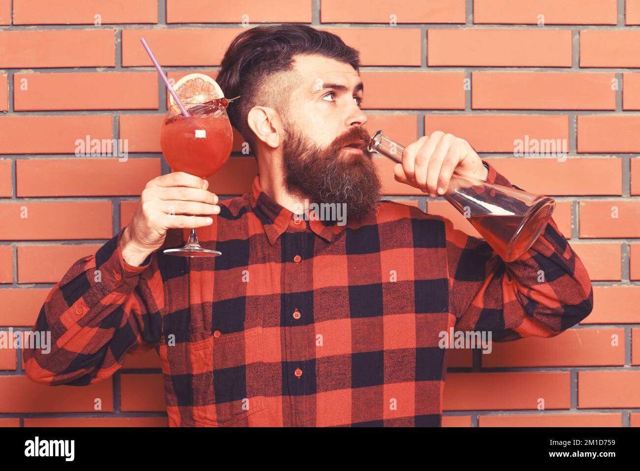 Barman with beard and strict face drinks out of bottle Stock Photo