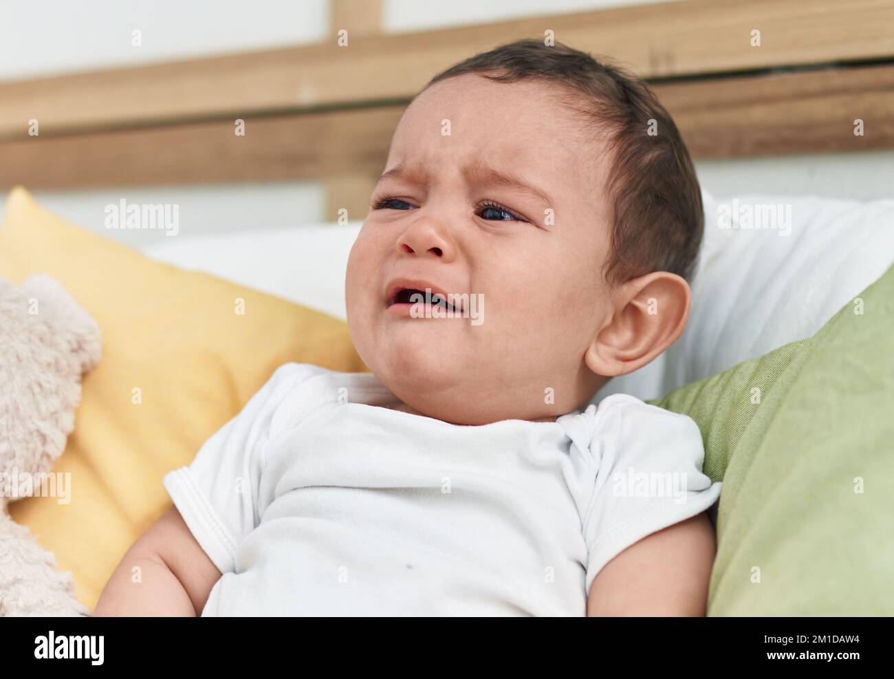 Adorable hispanic baby sitting on bed crying at bedroom Stock Photo - Alamy