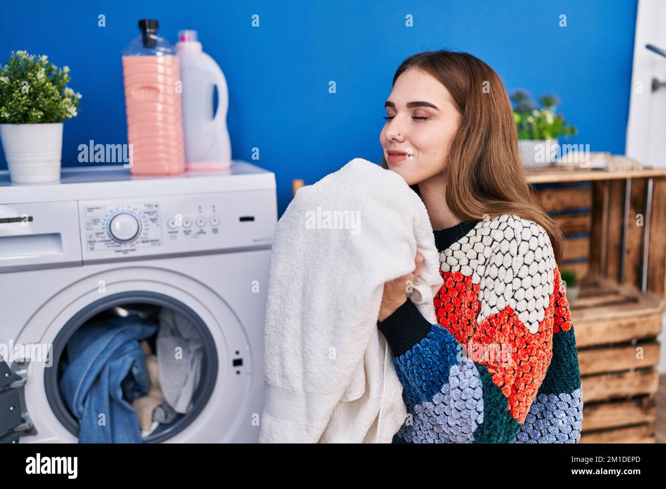 Young woman smelling towel washing clothes at laundry room Stock Photo