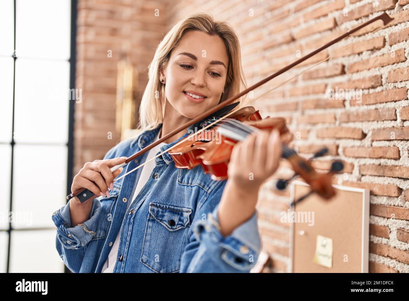 Young blonde woman musician playing violin at music studio Stock Photo ...