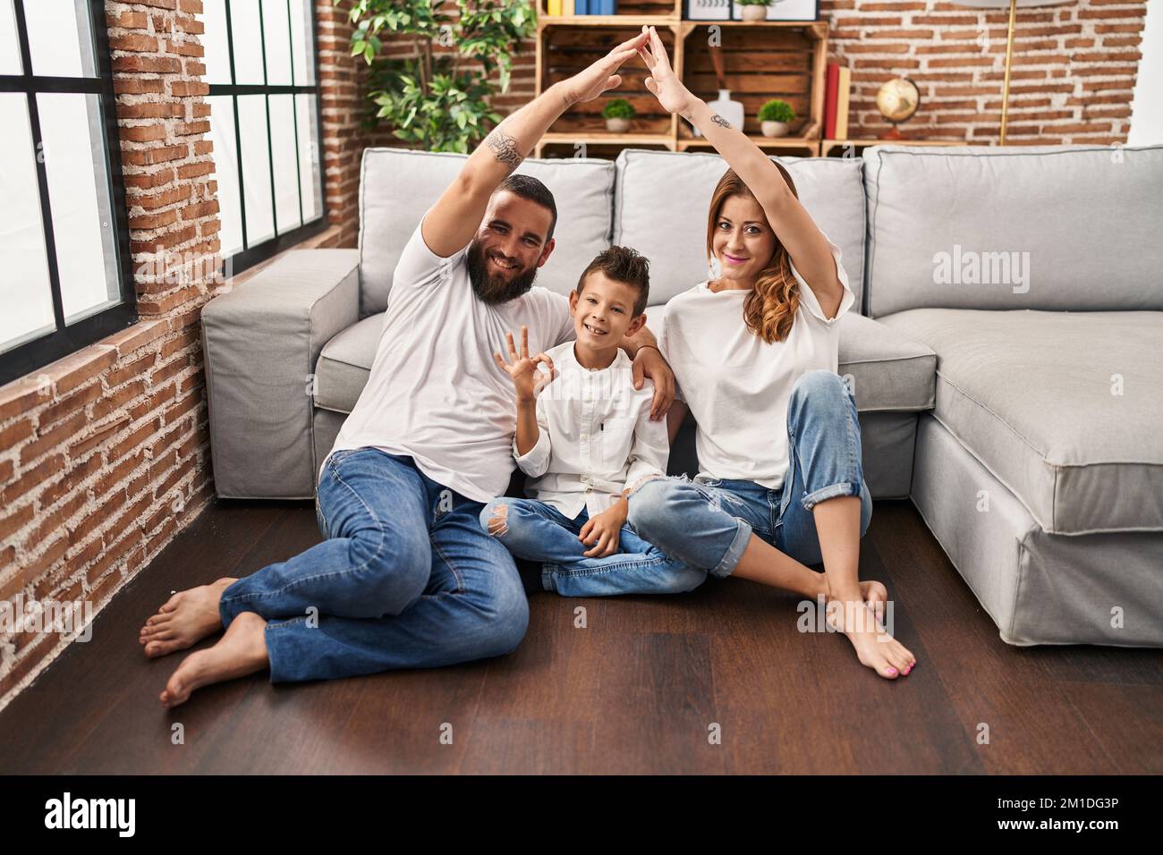 Family of three doing house shape with arms doing ok sign with fingers, smiling friendly gesturing excellent symbol Stock Photo