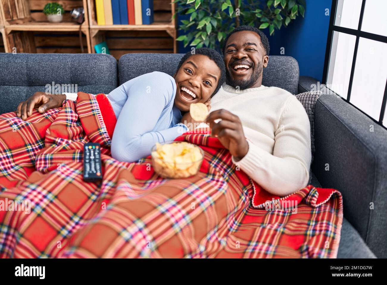 Young african american couple sitting on the sofa watching tv ...