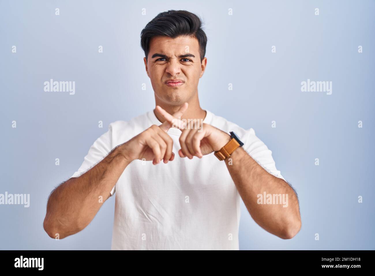 Hispanic man standing over blue background rejection expression ...