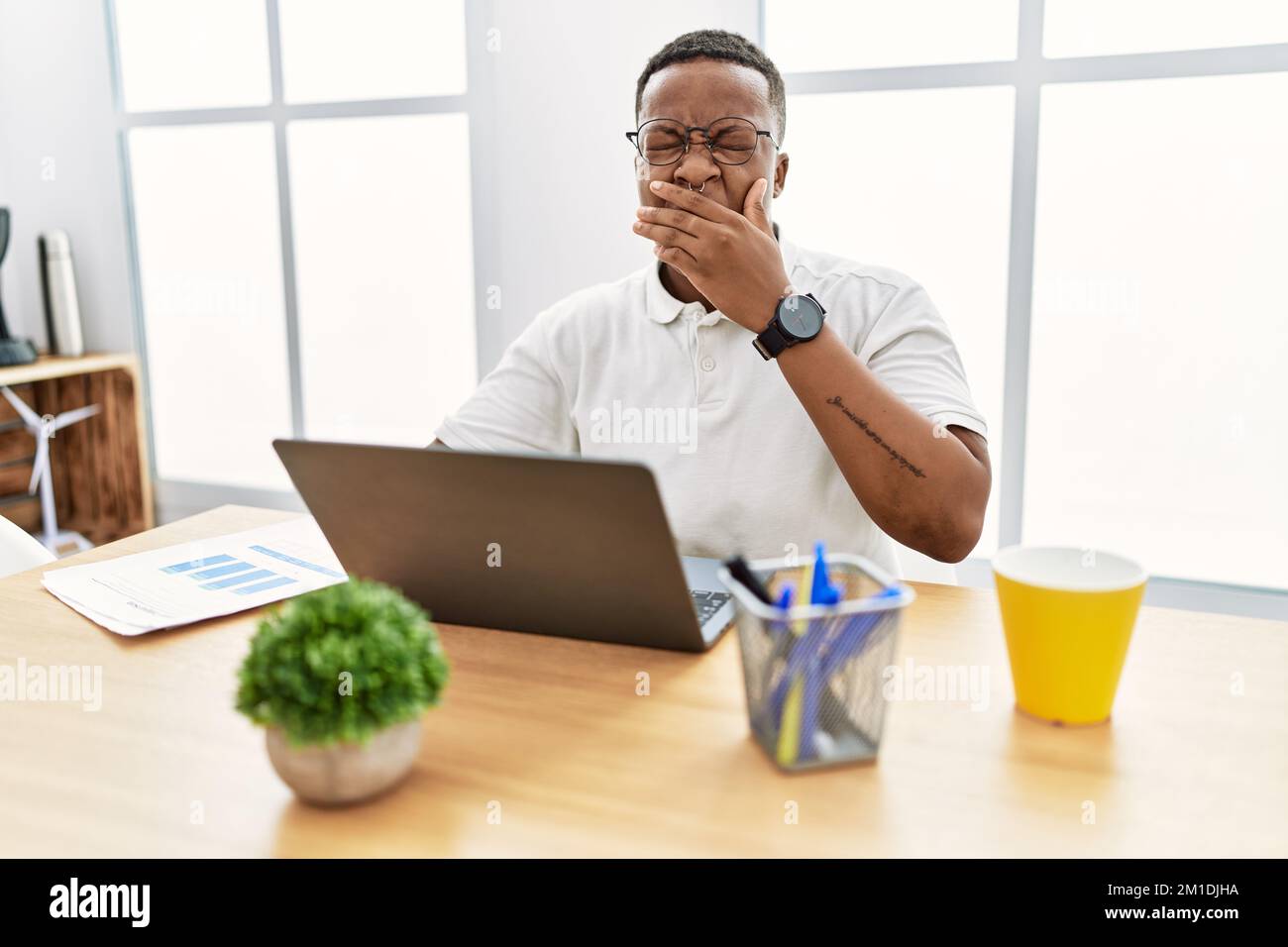 Young african man working at the office using computer laptop bored ...