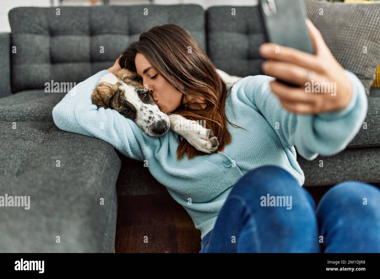 Young woman kissing and hugging dog making selfie by the smartphone at ...