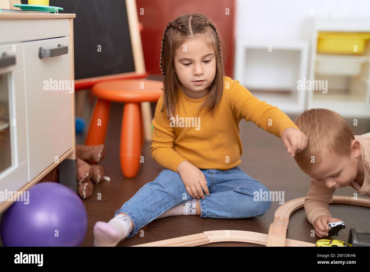 Adorable girl and boy playing with cars sitting on floor at ...