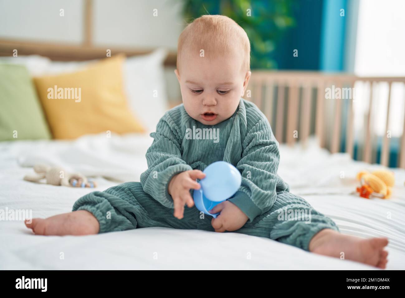 Adorable caucasian baby holding toy sitting on bed at bedroom Stock ...
