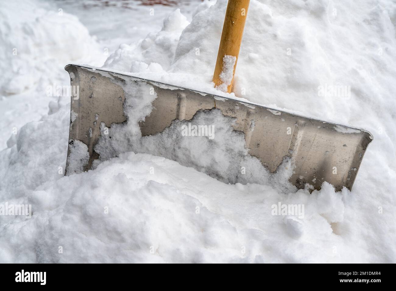 Snow shovel stuck in a high snow mountain as a symbol for winter service Stock Photo
