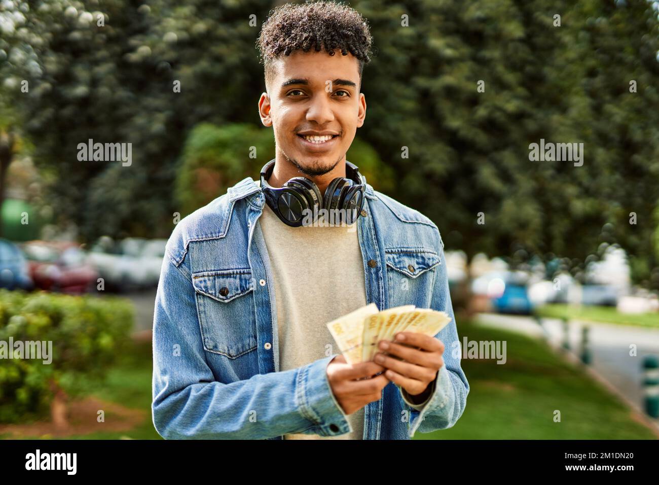 Hispanic young man holding 100 danish krone baknotes at the university campus Stock Photo