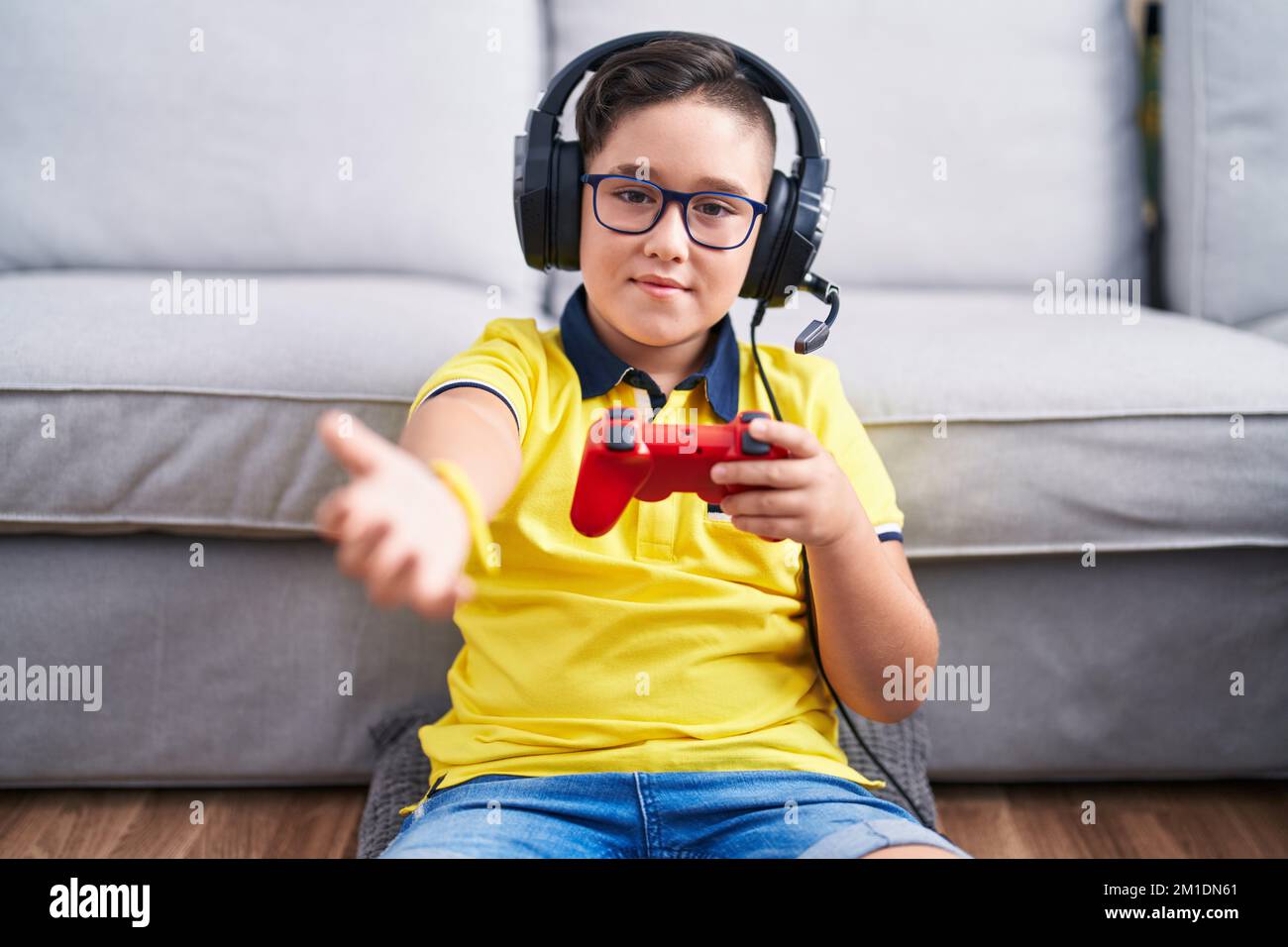 Kid Using Controller Young hispanic kid playing video game holding controller wearing ...