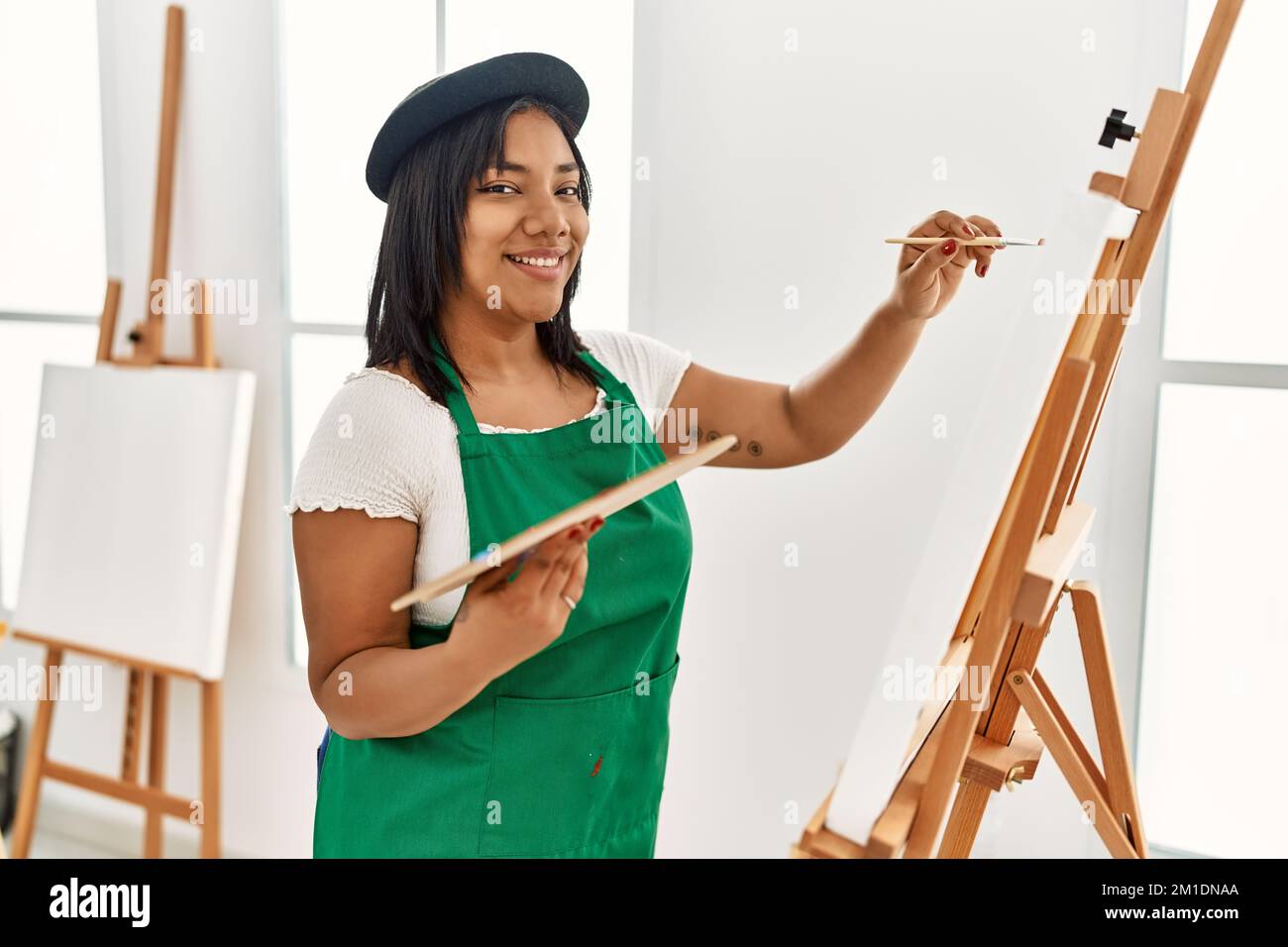 Hispanic brunette woman painting on canvas at art studio Stock Photo ...