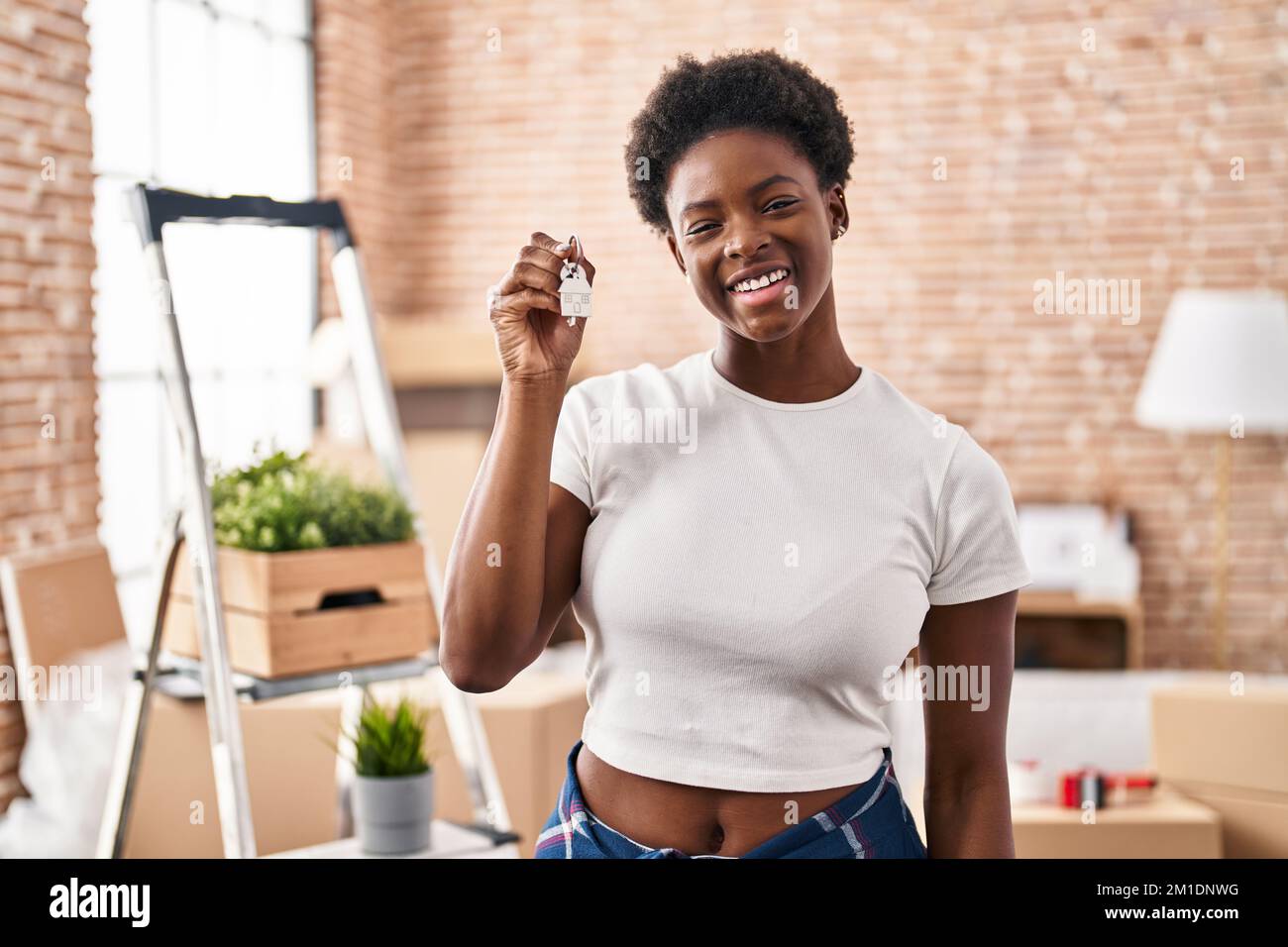 African american woman holding keys of new home looking positive and ...