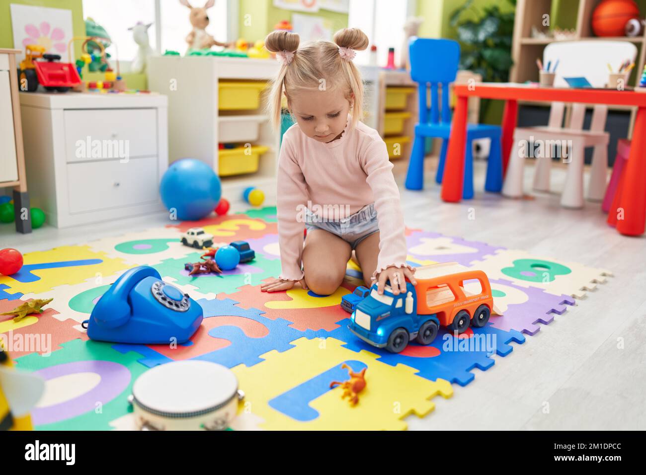 Adorable caucasian girl playing with cars toy sitting on floor at ...