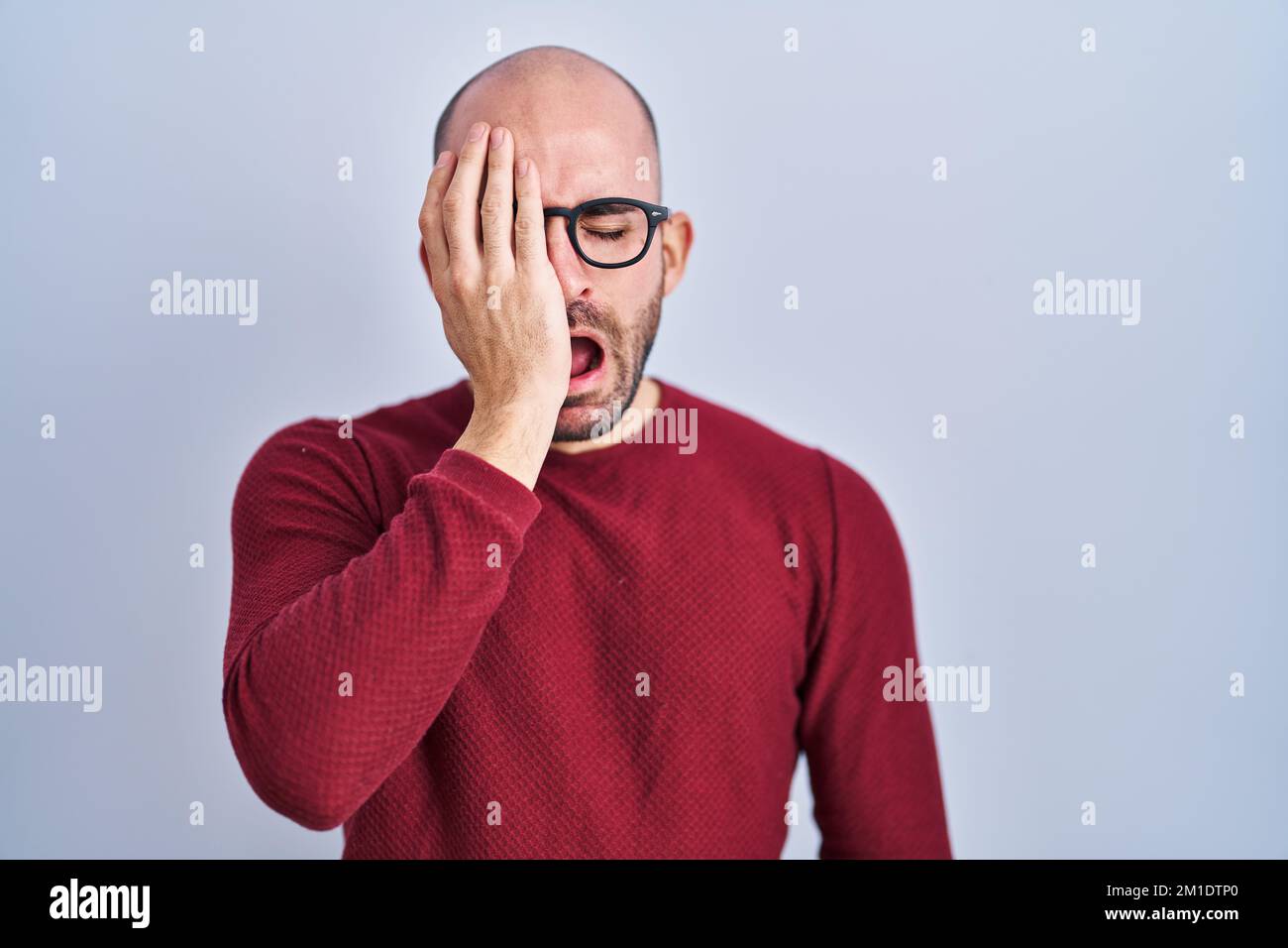Young bald man with beard standing over white background wearing