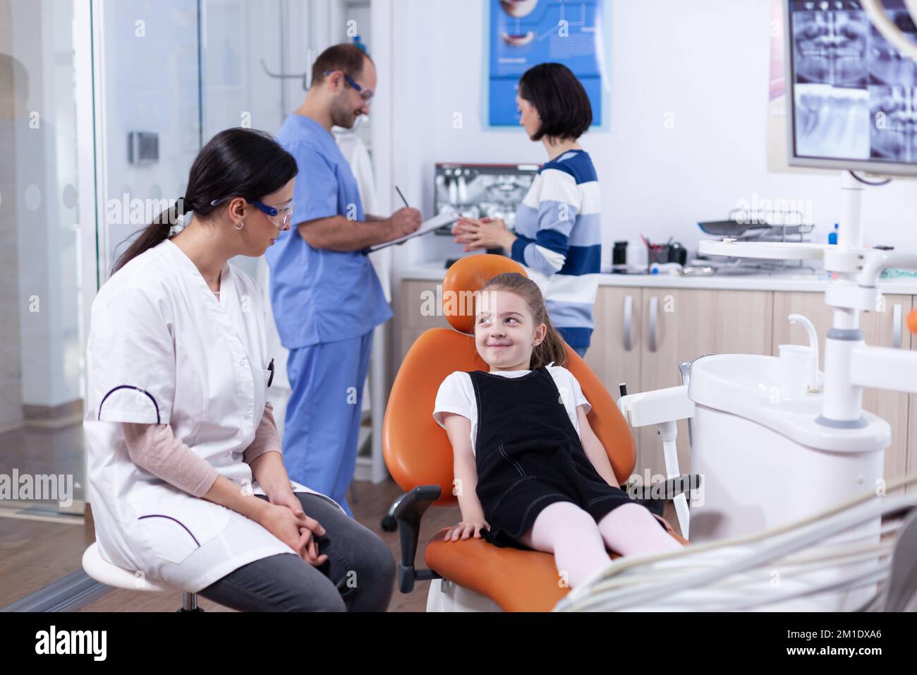 Shy little girl looking up at dentist doctor waiting teeth cavity