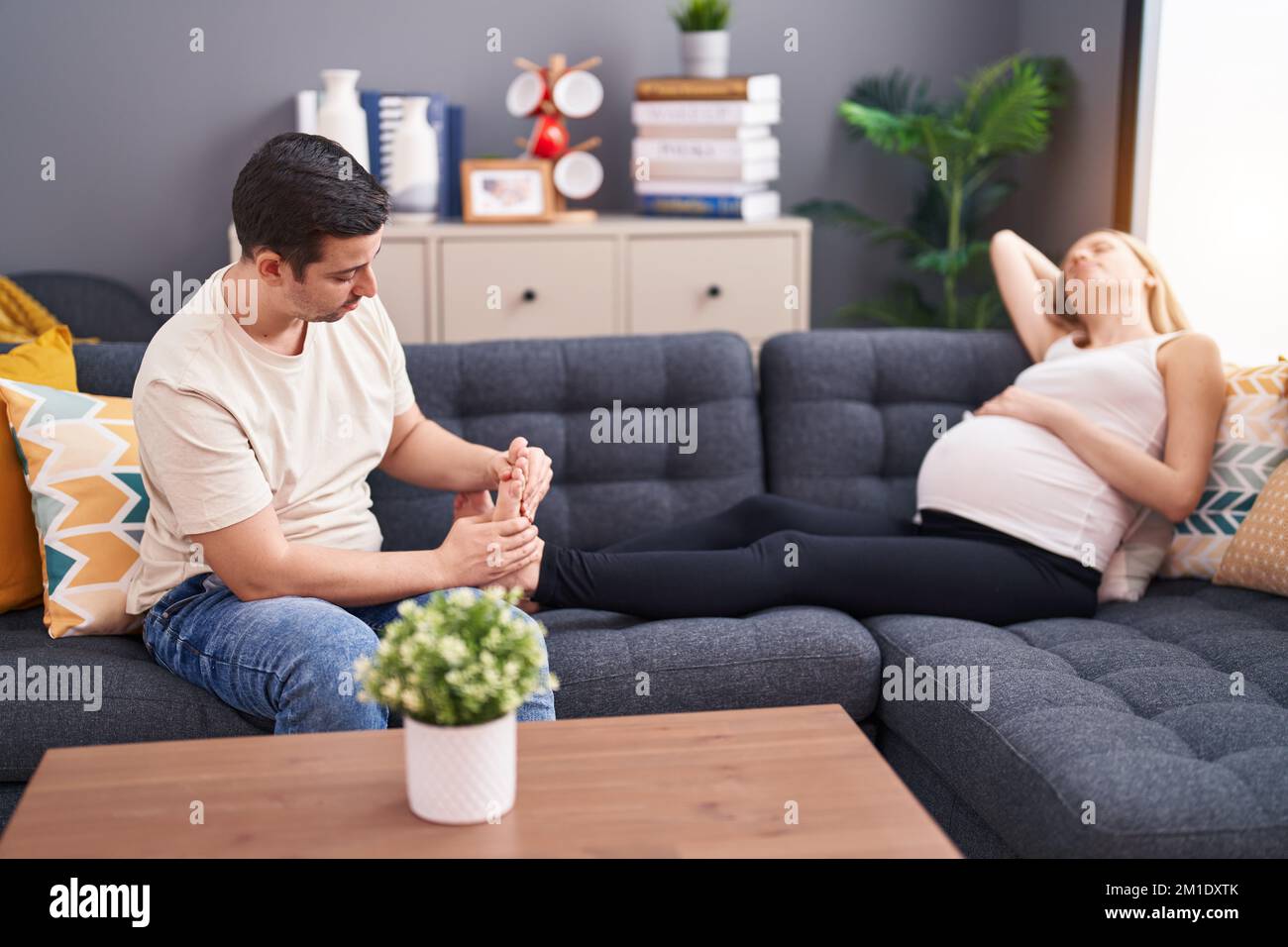 Man and woman couple expecting baby massaging feet at home Stock Photo