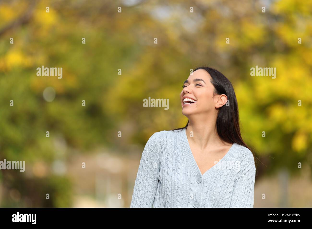 Happy woman walking in a park laughing looking at side a sunny day Stock Photo