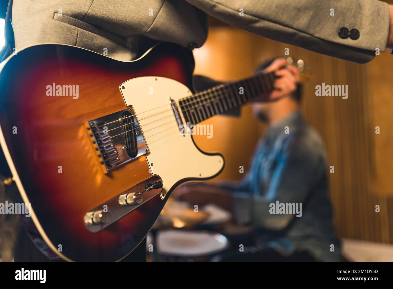 Band rehearsal. Camera focus on electric guitar held by unrecognizable