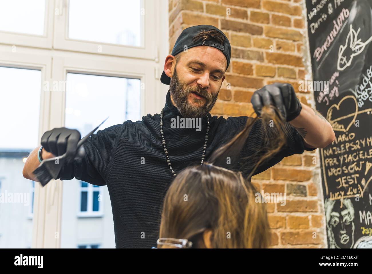 Male hairdresser cutting hair of an unrecognizable woman with scissors. High quality photo Stock Photo