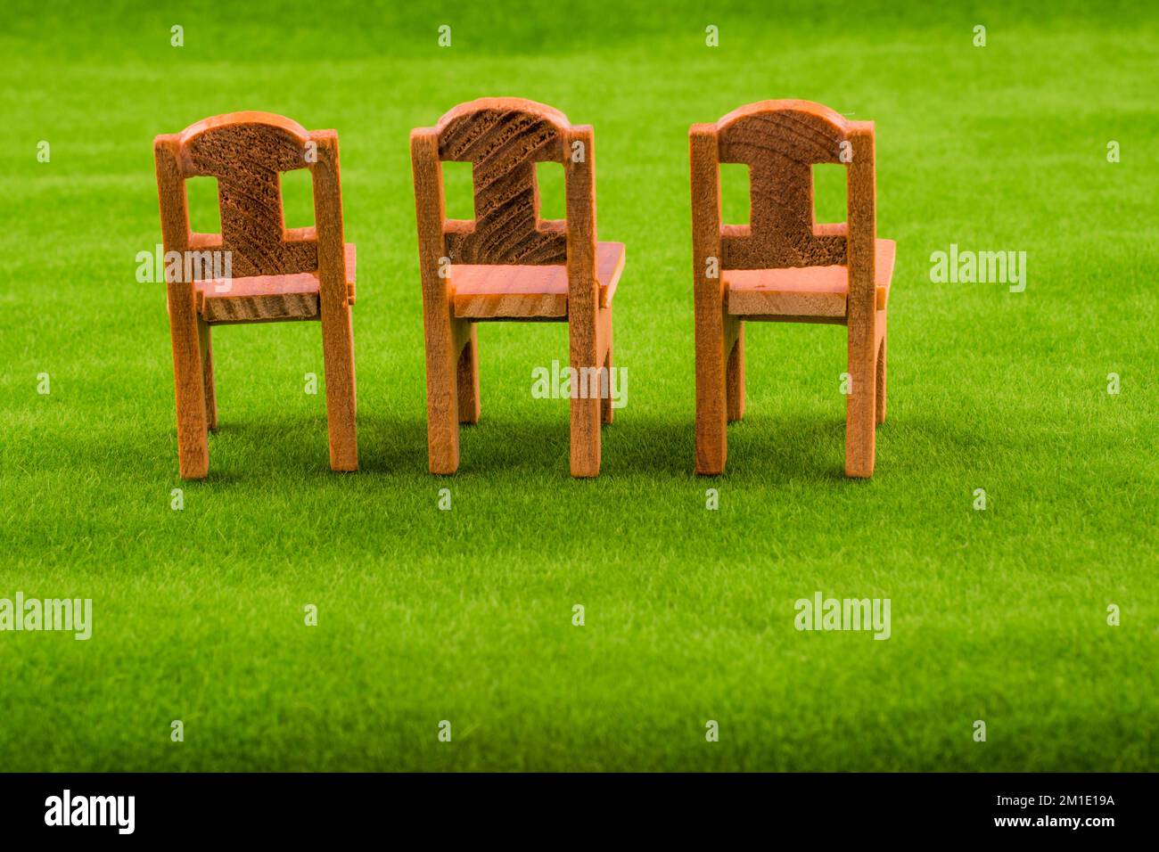 Little model wooden chairs on green fake grass Stock Photo