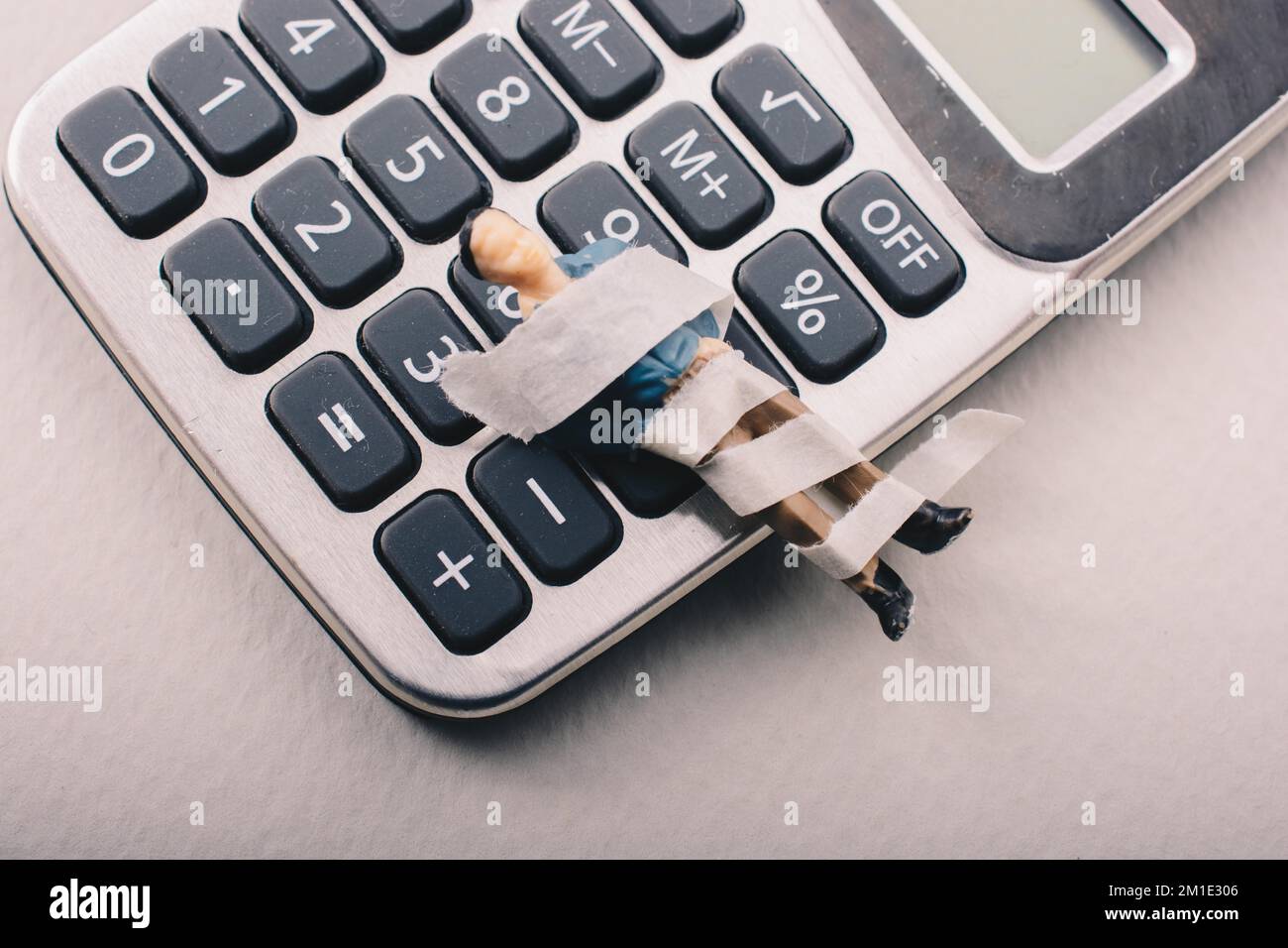 Tiny figurine of man model wrapped in bandages calculator Stock Photo