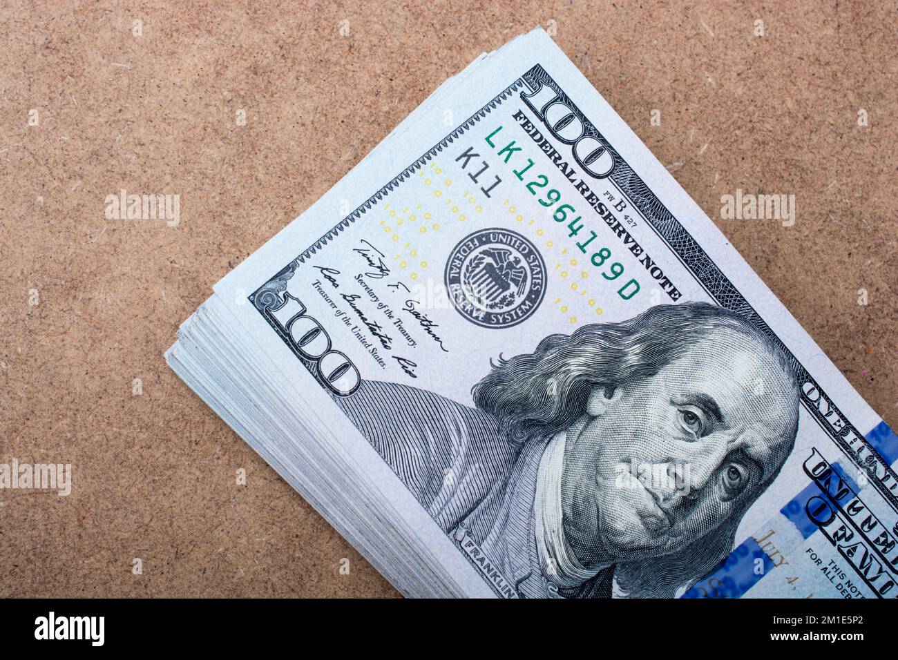 Hand holding banknote bundle of US dollar on a linen canvas background ...