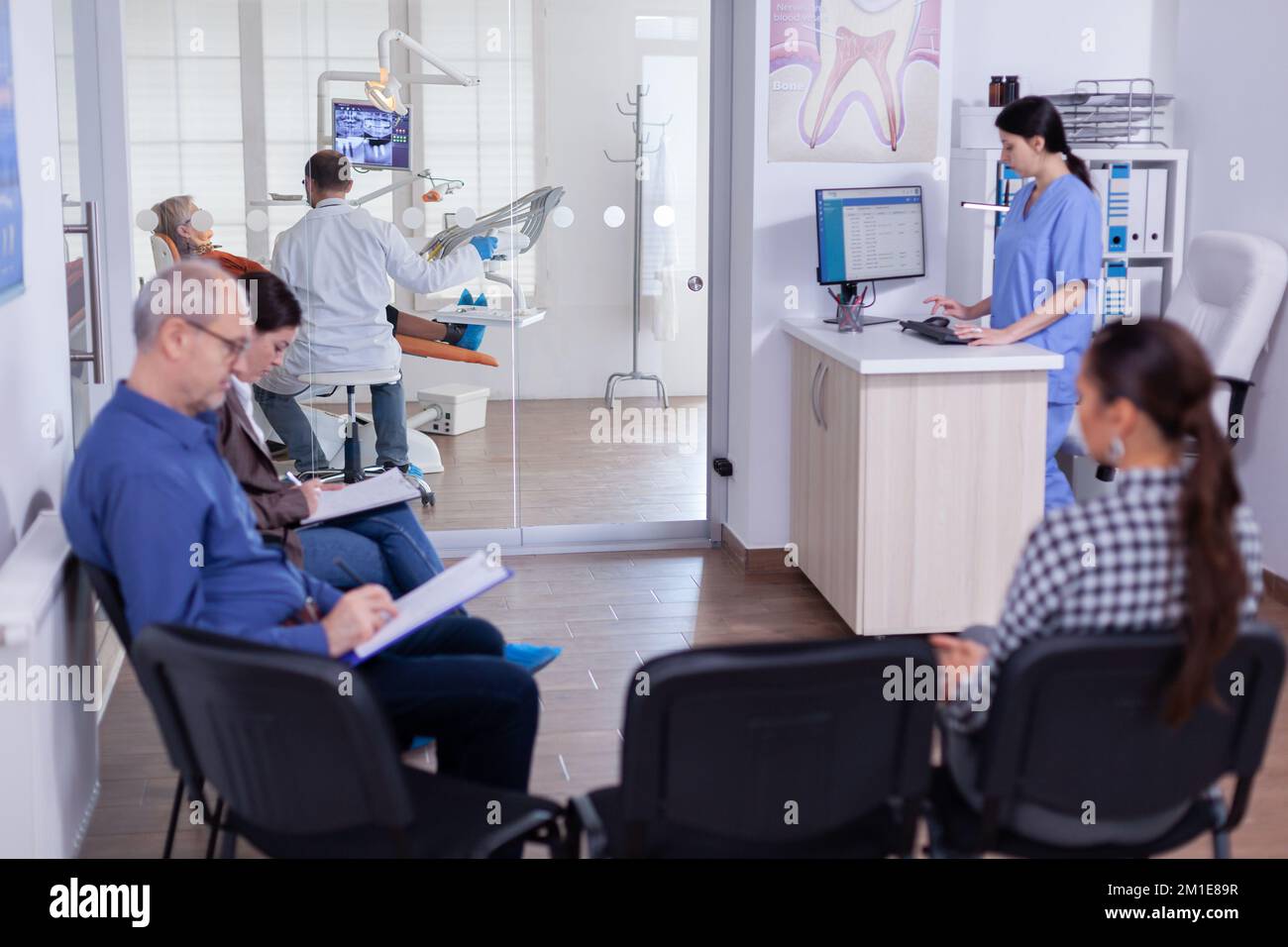Crowded stomatology waiting area with people filling form for dental ...